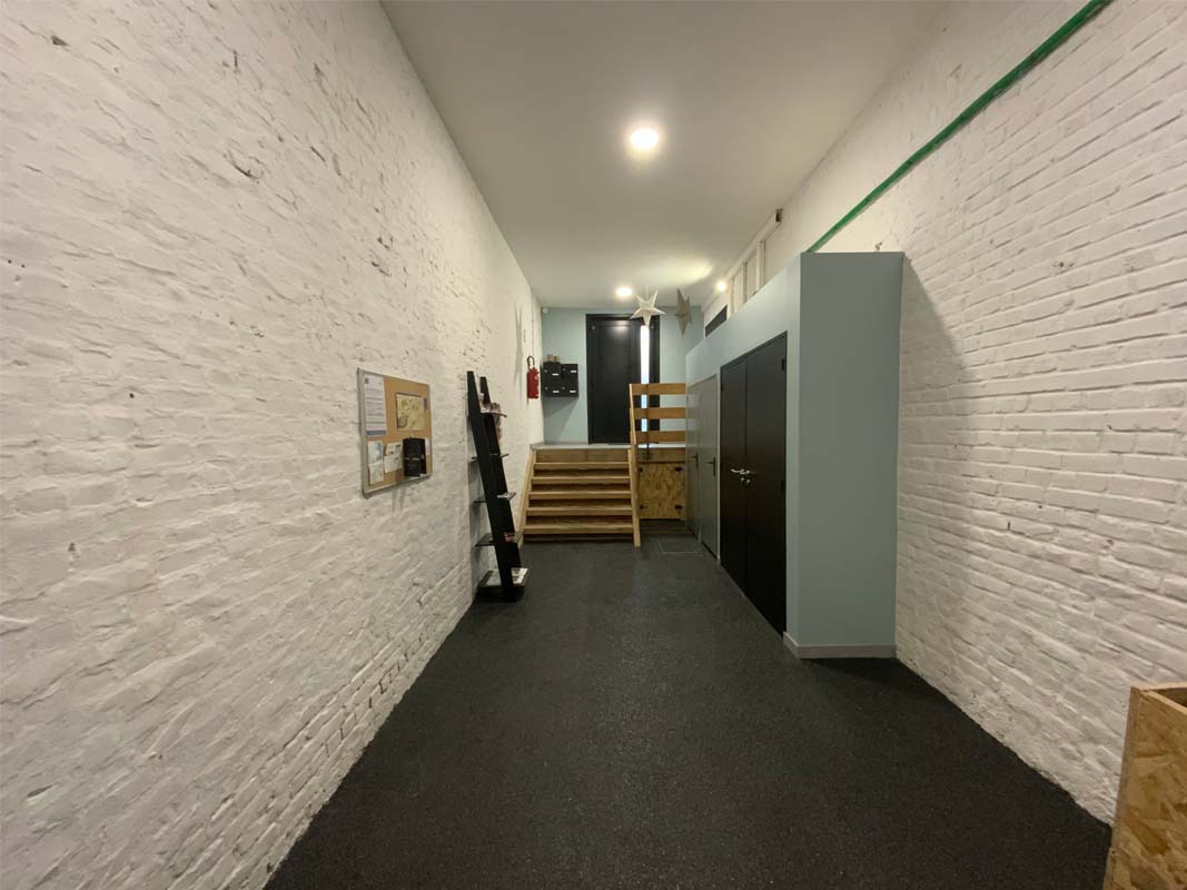 Entrance to the residence. White painted brick walls, sea green walls. Joinery and black floor. Wooden staircase. Gite hyper center Arras