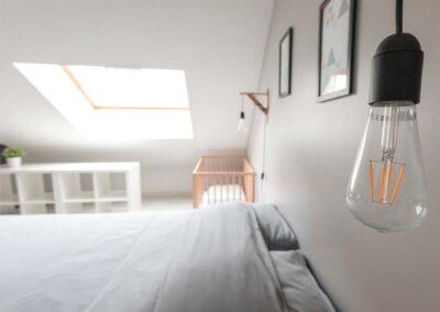 Master bedroom under the roof. Scandinavian atmosphere. Light gray bed linen, white furniture, light wood. Presentation hosts apartments lodgings Arras