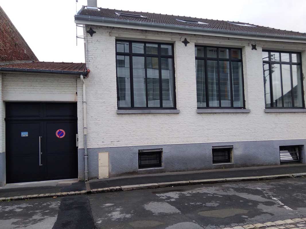 Residence At The Detour Of Places. 1A Rue des Augustines Arras. Large industrial type windows, doors of the residence in black wood. Gite hyper center Arras